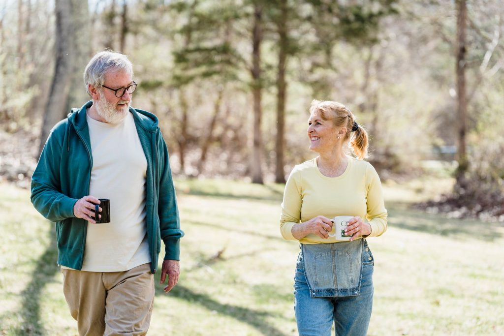 An older couple share a conversation while walking in a sunny park